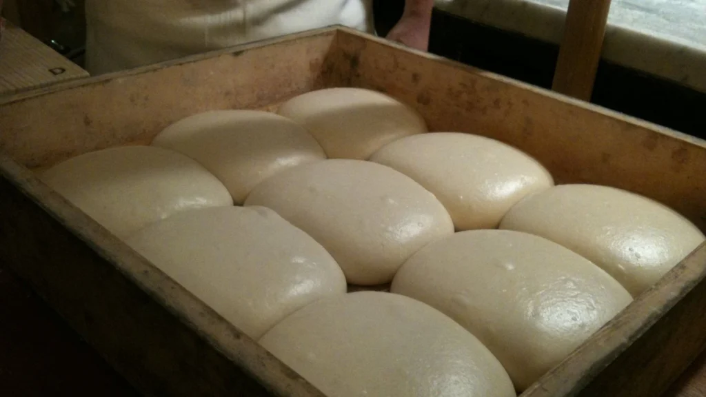 Balls of pizza dough rising in a wooden box